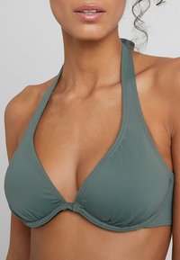 Zielony biustonosz bikini na szyję wykonany z gładkiego materiału. Posiada trójkątne miseczki z marszczeniem na środku oraz wąski regulowany pasek.
