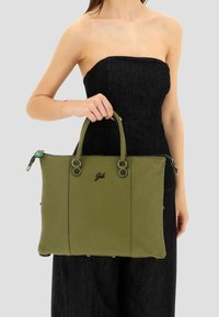 Borsa tote in pelle verde con due manici, superficie texture, dettagli in metallo nero e un logo sul davanti. Tasche laterali con zip.