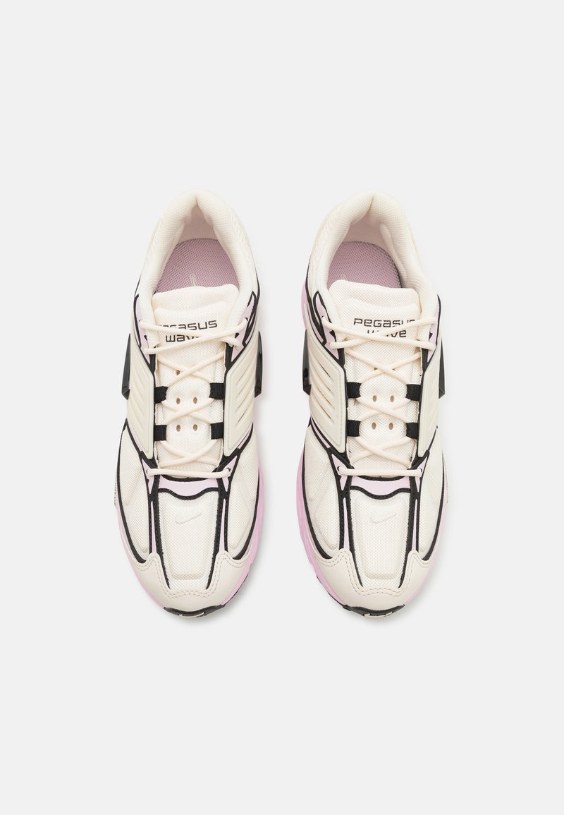 Zapatillas deportivas blancas con acentos negros, parte superior de malla texturizada, cierre de cordones, logotipo de la marca prominente y suela de goma rosa claro.