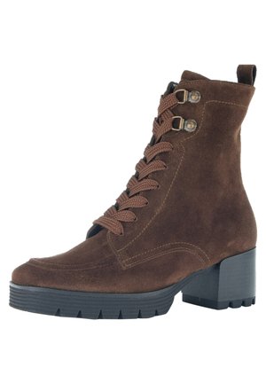 Braune Wildleder-Ankle Boots mit runder Zehenpartie, schnürbarem Vorderteil, metallischen Akzenten und einem klobigen schwarzen Absatz. Strukturierte Oberfläche und robustes Profil.