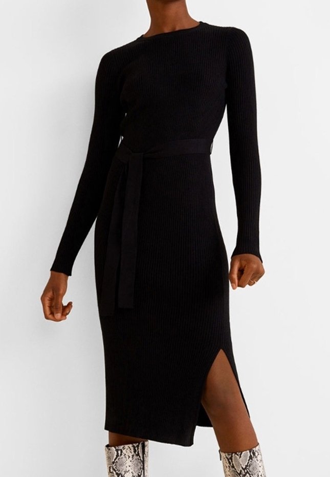 Femme portant une robe midi noire en maille côtelée à manches longues avec une ceinture à la taille et une fente latérale, associée à des bottes à motif peau de serpent.