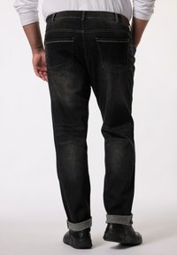 Mörka denimjeans med en lätt blekt textur, fem fickor, stickade detaljer och uppvikta fållar. Bärs med svarta sneakers.