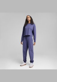 Sæt bestående af sweatshirt og joggingbukser i mørke lilla stof. Sweatshirten har et cropped design og elastiske manchetter; joggingbukserne har snøring i taljen og sidelommer.