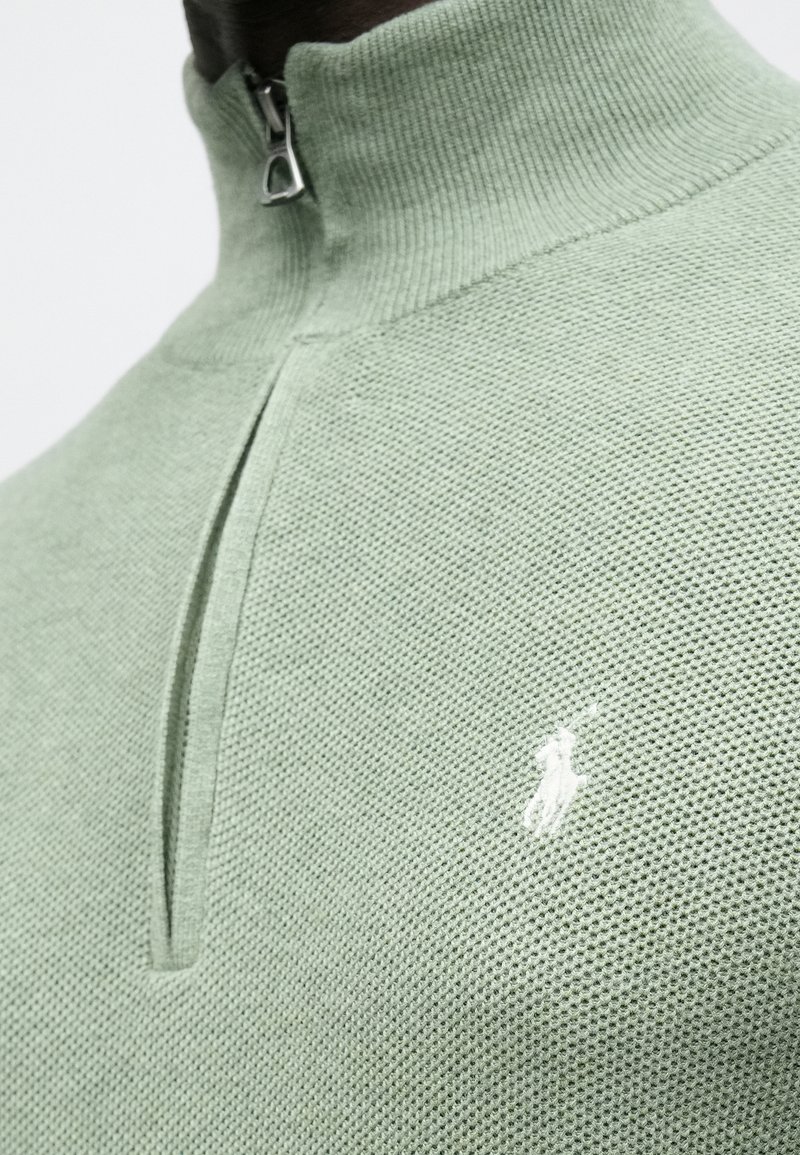 Maglione verde lavorato a maglia con colletto con zip, tessuto strutturato, caratterizzato da un piccolo logo bianco sul petto.