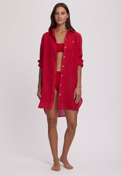 Κόκκινο λινό πουκάμισο με κλείσιμο με κουμπιά, μακριά μανίκια και πλαϊνές σχισμές, φορεμένο πάνω από ταίριαστο κόκκινο τοπ και μπικίνι.