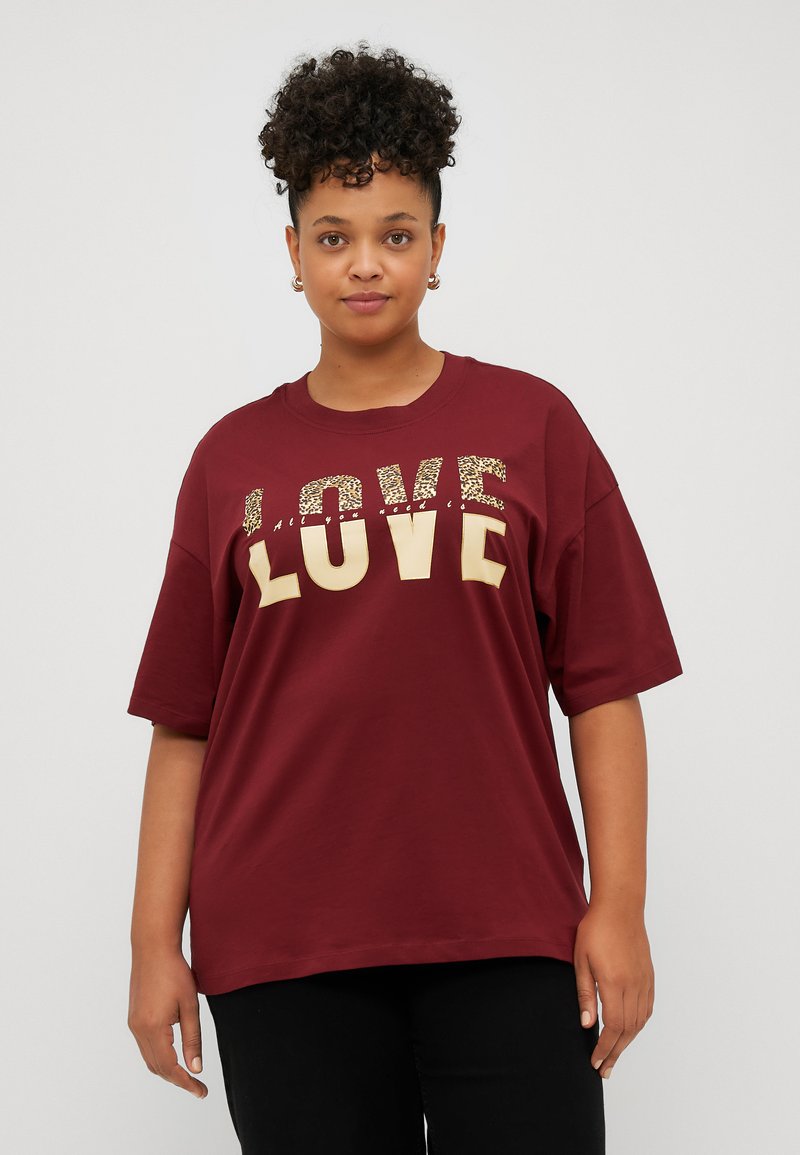 Maroon oversized t-shirt with leopard print and gold text saying "LOVE" on the front. Short sleeves and a round neckline, made of cotton.
