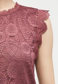 Ματζέντα αμάνικη δαντέλα μπλούζα με φλοράλ μοτίβο και περίτεχνη κυματιστή διακόσμηση με δαντέλα γύρω από τη μασχάλη και το λαιμό.