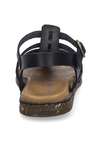 Schwarze Leder-Sandale mit mehreren über Kreuz verlaufenden Riemen, einem Schnallenakzent und einem geformten braunen Fußbett mit einer strukturierten Sohle.