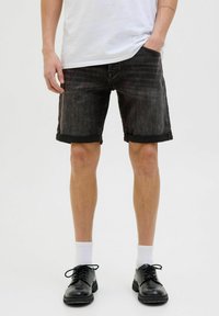 Șorturi din denim negre cu manșete răsucite, având un design clasic cu cinci buzunare. Asortate cu șosete albe până la gleznă și pantofi negri cu șireturi.