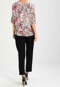 Flowy pink blouse with a floral pattern, three-quarter sleeves, and a keyhole back, paired with black tapered pants and black high heels.