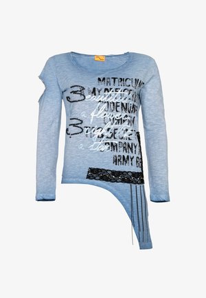 Vaaleansininen pitkähihainen paita mustavalkoisella tekstillä, mustalla pitsikoristeella, epäsymmetrisellä helmaosalla ja pienillä metalliniiteillä yhdellä hihalla.