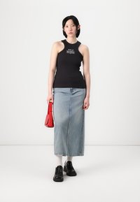 Zwarte geribbelde tanktop met witte tekst, lichtblauwe denim maxi rok, rode handtas en zwarte schoenen. Minimalistisch ontwerp en neutrale kleuren.
