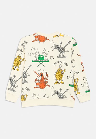 Kremno obarvan pulover z barvitimi risanimi liki in notami v igrivem vzorcu; z rebrastimi manšetami in robom.