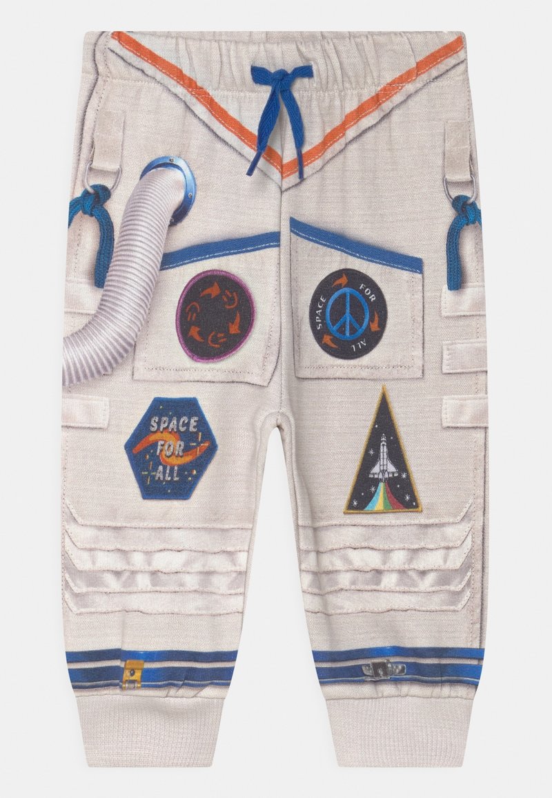 Pantalons de thème astronaute de couleur claire avec poches, accents bleus et motifs texturés. Présente divers patchs et dessins colorés liés à l'espace.