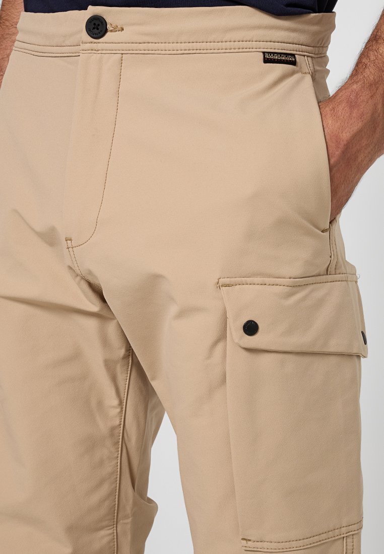 Pantaloni cargo beige con un design elegante, tessuto resistente, tasche laterali con bottoni a pressione neri e una vita standard.