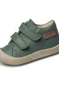 Chaussure en cuir vert avec deux bandes velcro, une semelle en caoutchouc beige et une étiquette marron portant la mention "NATURINO BAREFOOT". Texture lisse et forme arrondie.