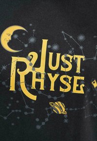 Melnas auduma t-krekls ar lieliem dzelteniem uzrakstiem "Just Rhyse", kurā ir redzami debesu motīvi, tostarp mēness un zvaigznes.