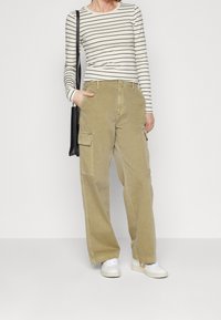 Khaki cargobyxor med rak passform, med två sidofickor och lätt tygkvalitet, i kombination med en randig långärmad topp.