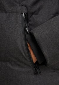 Zwarte pufferjack sectie met een ritszak, met een gladde stofstructuur en een contrasterende binnenvoering zichtbaar bij de opening van de zak.