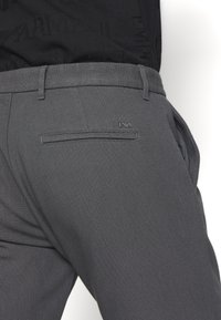 Grå texturerade byxor med slim fit, som har en enda bakficka, bälteningar och en subtil logotagg på midjebandet.