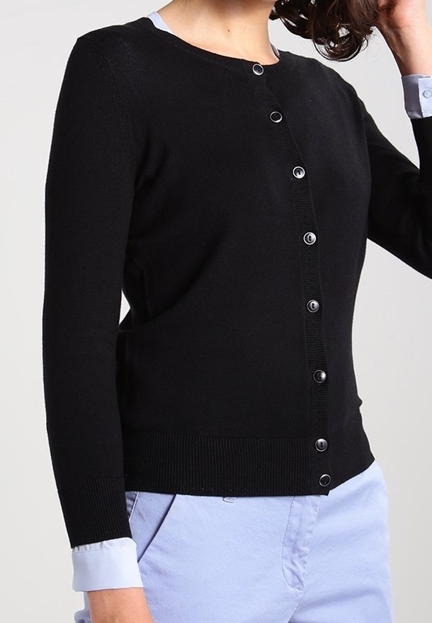 Svart cardigan med rund halsringning, långa ärmar och knappstängning framtill. Har ribbade muddar och fåll, tillverkad av mjukt stickat material.