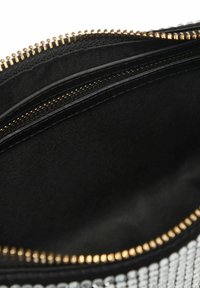 Svart clutch-väska med dragkedjestängning och guldiga detaljer. Inuti finns foder i slät tyg och en extra ficka med dragkedja.