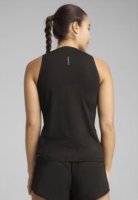 Débardeur noir sans manches en tissu lisse, avec un col montant et un petit logo en arrière. La coupe est ajustée.
