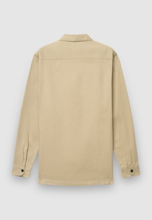 Chemise beige à manches longues en coton. Dispose d'un col, de poignets boutonnés et d'une coupe droite ; texture lisse sans motifs.