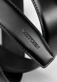 Zwarte leren sandalen met brede banden, een gladde textuur en subtiele stiksels. "WITTCHEN" logo verdiept in één band.
