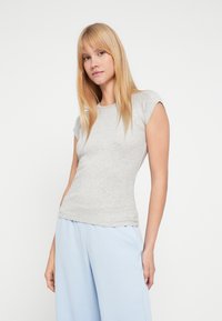 Ανοιχτό γκρι εφαρμοστό t-shirt με κοντά μανίκια, στρογγυλή λαιμόκοψη και απαλό βαμβακερό ύφασμα, συνδυασμένο με ανοιχτό μπλε χαλαρό παντελόνι.