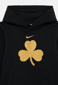 Czarna bluza z kapturem z dużym złotym wzorem koniczyny o teksturze drewna oraz mniejszym złotym logo Nike Swoosh na górnej części klatki piersiowej.