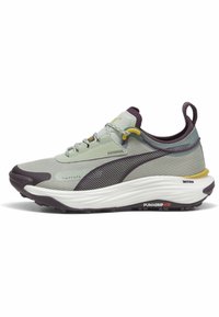 Light green athletic shoe with a textured upper, purple accents, rounded toe, reflective details, and a thick white sole with traction pattern.