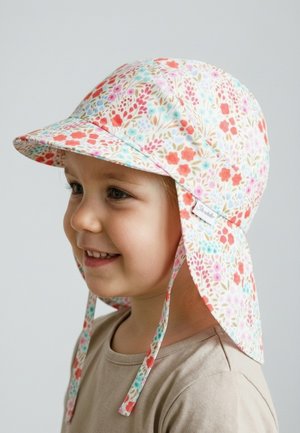 Smiling child wearing a floral-patterned sun hat with neck flap and adjustable chin straps, light beige shirt, neutral background.