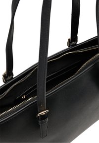 Czarna skórzana torba typu tote z dwoma paskami, złotym metalowym wykończeniem, zapinanymi na zamek przegrodami oraz teksturowaną powierzchnią. W środku znajduje się kieszeń organizacyjna.
