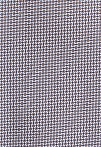 Motif géométrique répétitif de petits carrés avec des formes losanges alternées en tons noir, blanc et marron.