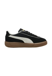 Zapatilla de ante negra con acentos blancos, suela de goma marrón y cordones negros. Presenta un logo dorado en la lengüeta y un diseño de perfil bajo.