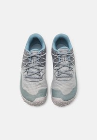Szare i niebieskie buty sportowe mają oddychającą siateczkową cholewkę, odblaskowe akcenty oraz teksturowaną gumową podeszwę z wzorzystym bieżnikiem.
