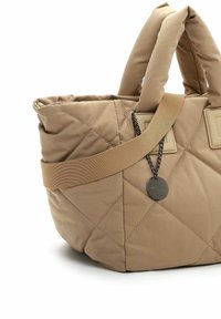 Quilted tan handbag with dual handles and an adjustable strap. Features a metal tag and accent stitching, made from soft fabric.