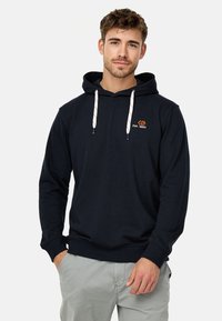 Mørkeblå hættebluse med hvide og røde snore, prydet med et broderet logo på brystet. Blødt stof, afslappet pasform.