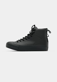 Zwarte hoge sneakers van gestructureerd leer, met een ronde neus, verhoogde rubberen zool, vetersluiting aan de voorkant en een lus aan de achterkant.