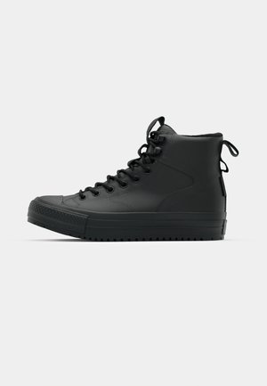 Black high-top sneakers made of textured leather, featuring a round toe, raised rubber sole, lace-up front, and pull tab at the back.