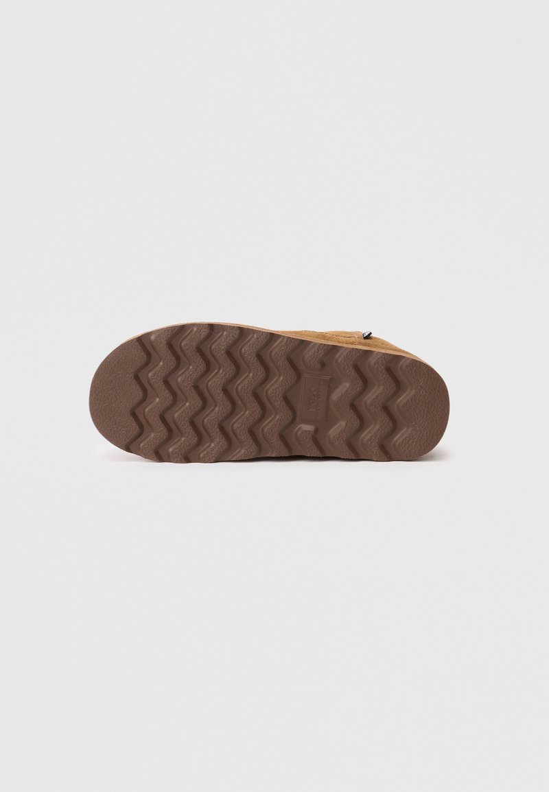 Semelle en suède avec un motif de bande en caoutchouc en zigzag, de couleur marron et surface texturée. Plate avec un talon arrondi pour une meilleure traction.
