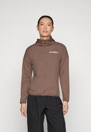 Veste zippée marron avec capuche, fabriquée en matériau léger et texturé. Présente le logo "Terrex" sur le côté supérieur droit.