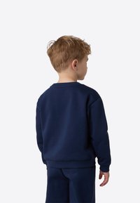 Marineblå genser i mykt stoff, rund hals og ribbestrikkede mansjetter. Bildet viser ryggen med minimale sømmer og enkelt design.