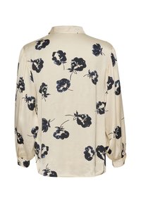 Long-sleeved blouse made of soft, cream fabric with navy floral print. Features a collared neckline and elasticized cuffs for fit.