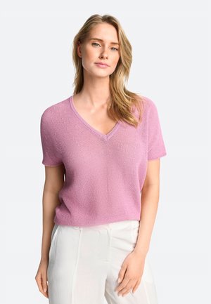 Kurzärmliger V-Ausschnitt Pullover aus hellrosa Strickmaterial, mit einem strukturierten Muster und lockerer Passform. Kombiniert mit hellen Hosen.