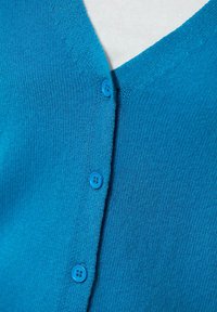 Türkiser gestrickter Cardigan mit V-Ausschnitt, fünf blauen Knöpfen und feiner Textur. Das Design ist schlicht ohne erkennbare Muster.