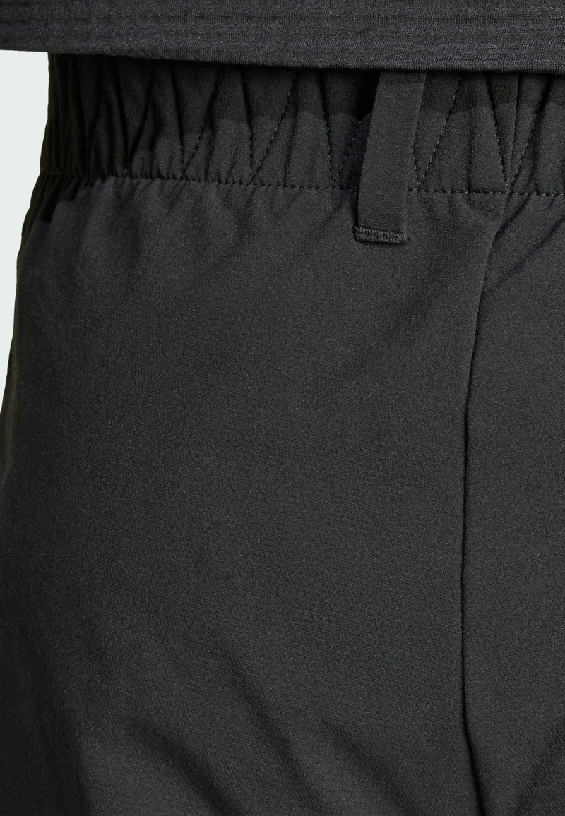 Zwarte sportbroek met een textuurstof, elastische tailleband en stikdetails, die een soepele en flexibele uitstraling heeft.