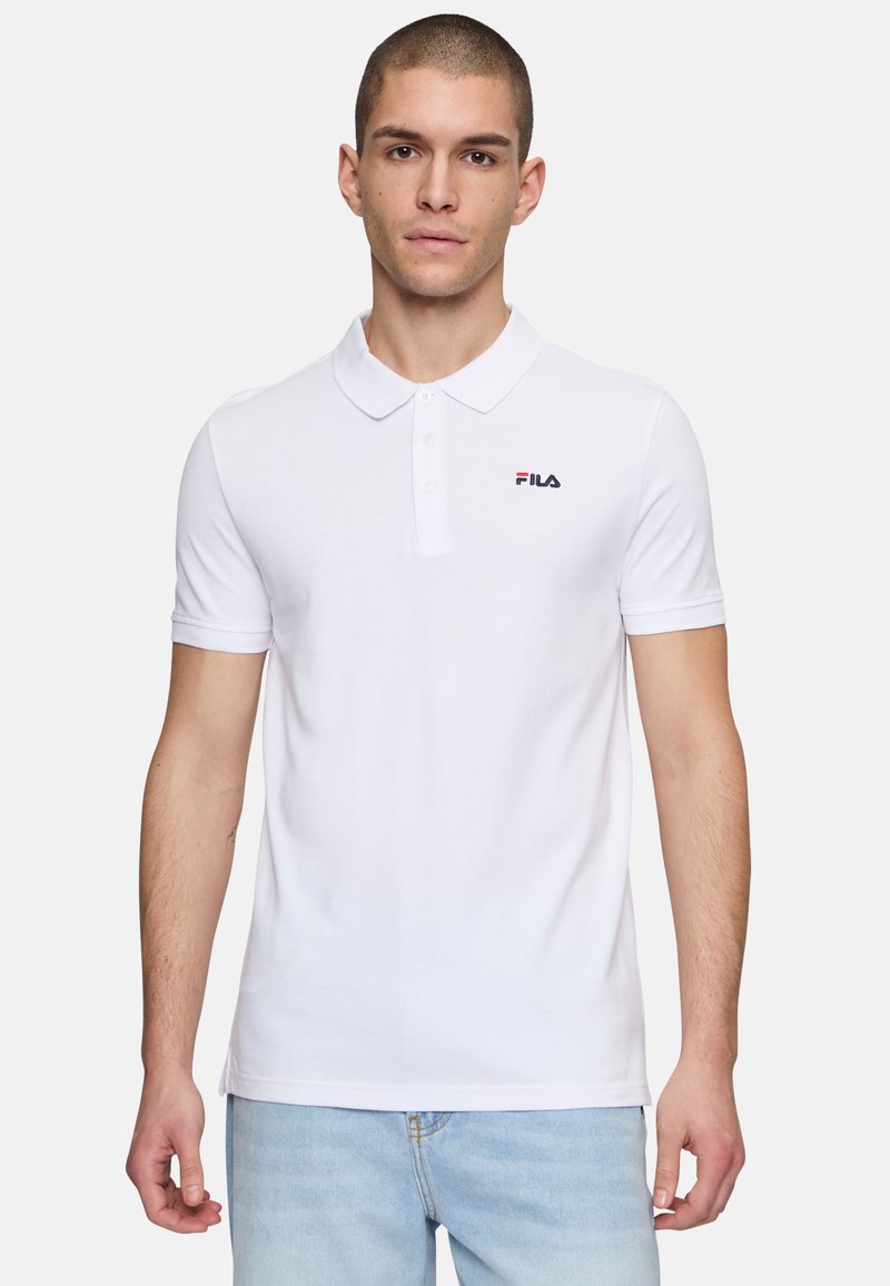 Valkoinen t-paita, joka on valmistettu puuvillasta ja jossa on kaksinappinen kaulus, lyhyet hihat sekä pieni Fila-logo vasemmassa rinnassa.