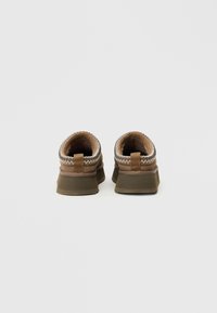 Brūni apavi ar teksturētu augšdaļu, kontrastējošām šuvēm un izturīgu zoli. Zems griezums ar vilkšanas cilpiņu uz papēža.